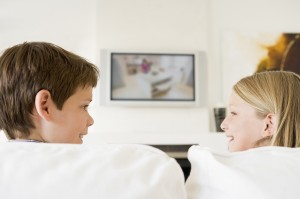 Young boy and young girl in living room with flat screen televis